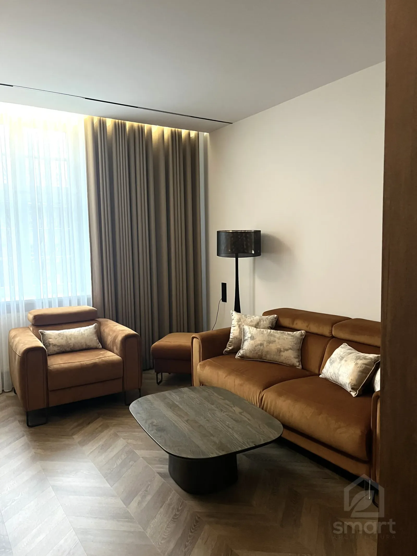 Narożnik salonu z fotelem, sofą i owalnym stolikiem na jodełce