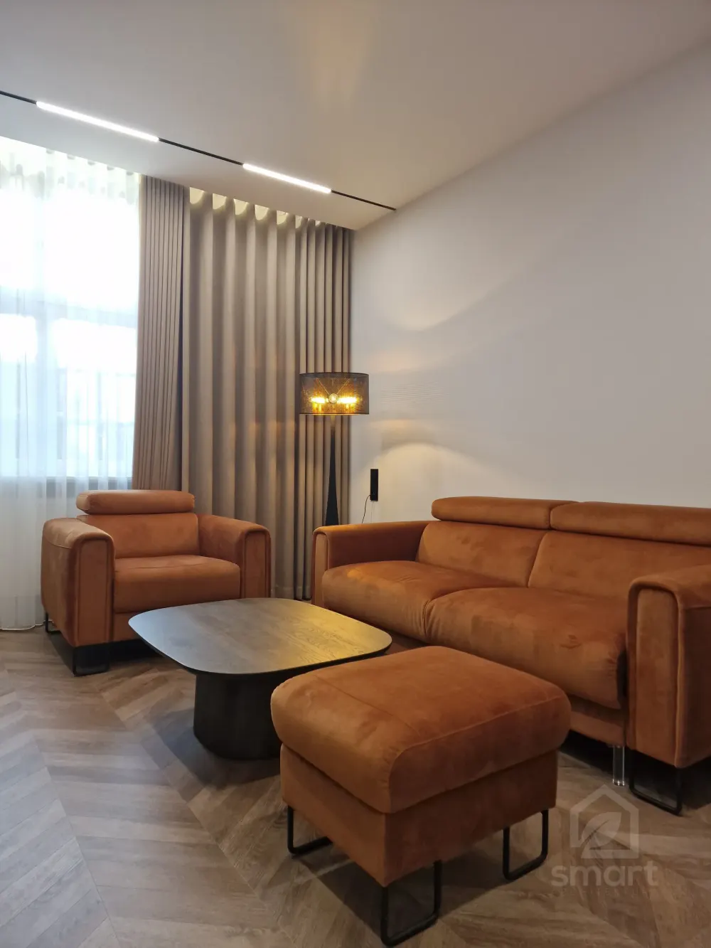 Salon z sofą, pufem i lampą podłogową przy oknie