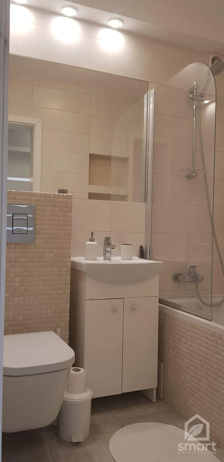 Łazienka w beżowym gresie z mozaiką, białą szafką umywalkową, wanną i podwieszanym WC