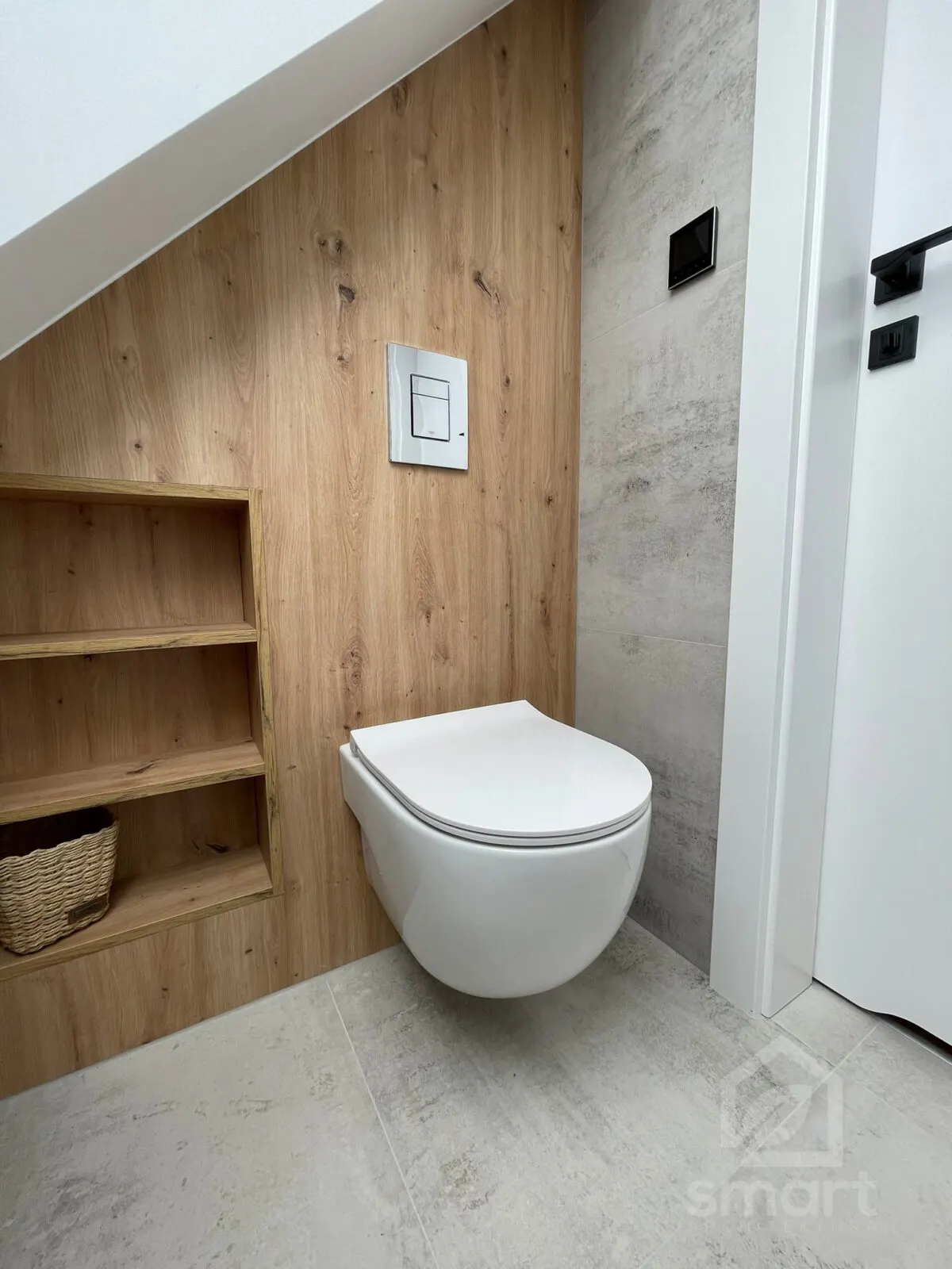 WC na tle ściany w dekorze drewna z wnęką na półki i szarymi płytkami